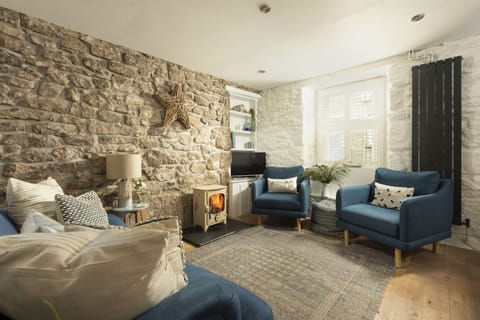 Living room with exposed stone wall and wood burning stove - Happy Days Cottage