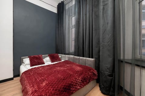 Modern studio interior with a comfortable sleeping area and dark, elegant finishes.