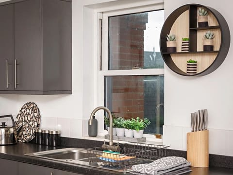 Kitchen sink area with countertop, dish rack, and window.