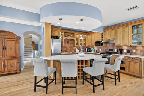 Spacious, high-end kitchen featuring custom wood cabinetry, a large center island, and warm coastal design accents.