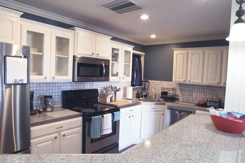 Modern full kitchen with stainless steel appliances and island seating.