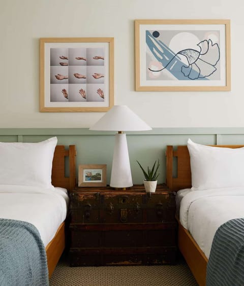 Twin beds with soft linens, warm lighting, and framed wall art