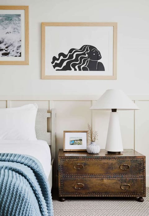 Clean bedside table with lamp and framed wall art