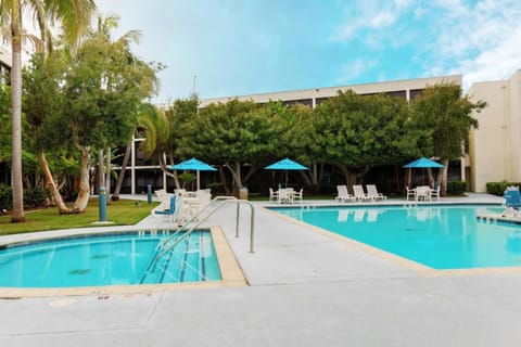 Outdoor pool with trees and blue umbrellas