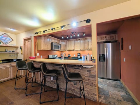 Your spacious kitchen invites culinary adventures with warm wood cabinets, modern stainless appliances, and a breakfast bar perfect for morning coffee.