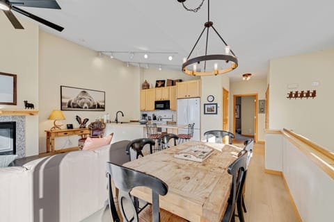 Gather around your rustic wooden dining table beneath the warm chandelier glow, while the open kitchen invites culinary adventures.