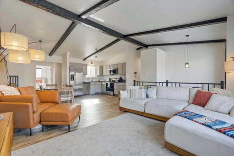 The open-concept main floor connects the kitchen, dining, and living areas. Vaulted ceilings with exposed beams and wood-style flooring create a spacious and cohesive environment for the whole group.