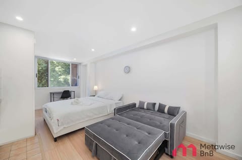 Spacious open-plan studio featuring a comfortable queen-sized bed and a sofa that can be converted into a sofa bed, offering flexible sleeping arrangements with clean, minimalist styling.