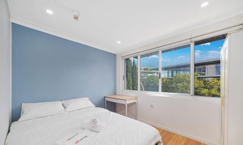 Minimalist bedroom showcasing a cozy queen-size bed and natural light from wide windows.