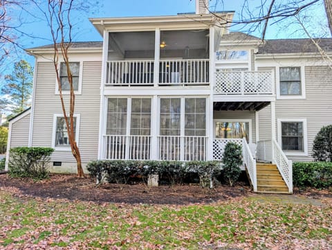 15002 Tall Pines Ct - Private Screened-In Retreat - This rear view of the property highlights the expansive two-story screened porch, offering a shaded and private outdoor area to enjoy the coastal breeze. The well-maintained grounds and mature trees provide a serene backdrop for your stay.