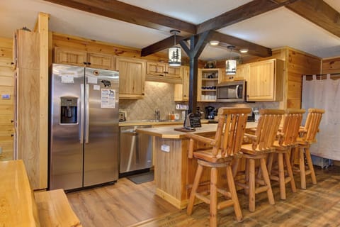 Gather around this stunning rustic kitchen with warm wood cabinetry, stainless steel appliances, and cozy breakfast bar seating.