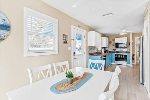 Gather around your bright dining table while savoring meals prepared in the fully-equipped kitchen with coastal blue cabinetry and modern appliances.