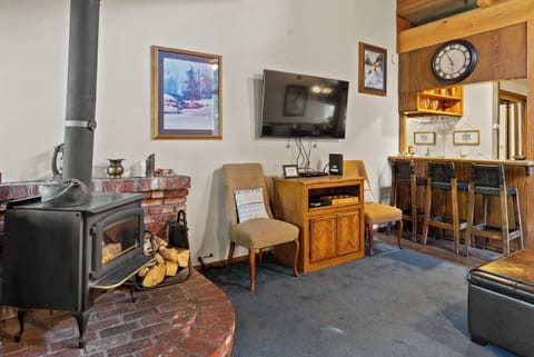 Open living area with vaulted wood ceilings, a cozy wooden fireplace, and a private balcony.