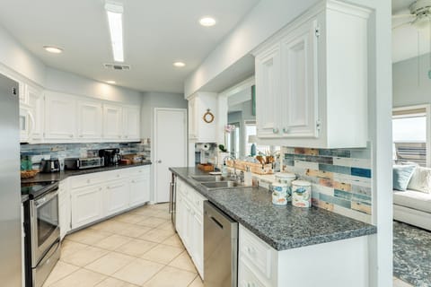 Gourmet kitchen features granite countertops, white cabinets, and coastal tile backsplash