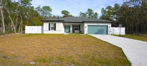 Bright coastal home featuring a spacious driveway and private fenced yard.