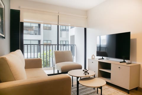 Bright living room with balcony access and a flat-screen TV.