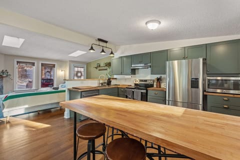 Bright, fully equipped kitchen with room for everyone to gather - windows frame the surrounding trees