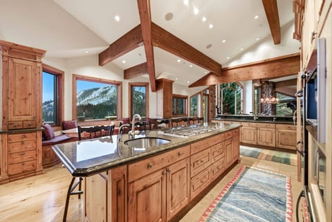 Open kitchen and dining space:
Open-concept kitchen and dining area with granite island, wood beams, and expansive windows designed for entertaining.