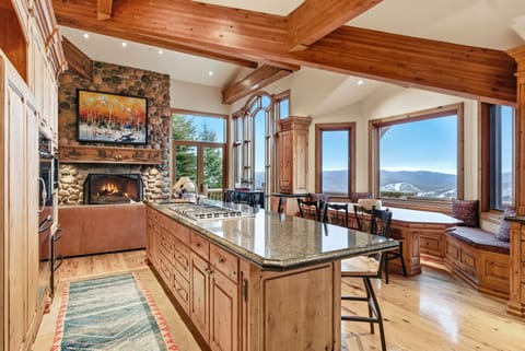 Kitchen island with mountain backdrop:
Spacious kitchen with large center island, bar seating, stone fireplace, and floor-to-ceiling windows with mountain views.