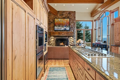 Kitchen island and living area:
Luxury kitchen island with granite countertops, wood cabinetry, and a view into the living area with stone fireplace.