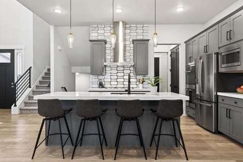 Sleek, chef-style kitchen with a spacious waterfall island, premium stainless appliances, and seating for casual meals or après-ski gatherings.