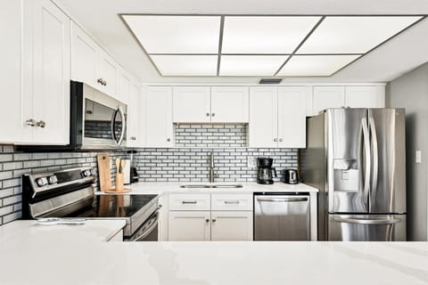 Your sleek kitchen awaits with stainless steel appliances, white cabinets, and subway tile backsplash—perfect for preparing meals during your stay.