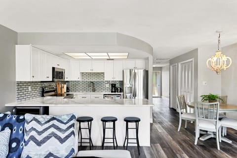 Your modern kitchen invites culinary adventures with sleek white cabinets, granite counters, and a breakfast bar perfect for morning coffee.