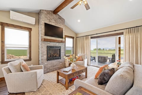 Living room with cozy fireplace, sofa, chairs, & breathtaking mountain views