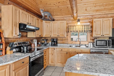 Spacious log kitchen with granite counters, stainless appliances, island seating