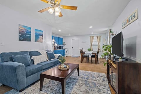 Comfortable blue sofas and beach-themed decor create a warm and welcoming space. The open layout connects seamlessly to the dining and kitchen areas. 