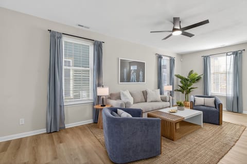 Bright living room w/ comfy seating, TV & large windows bringing in natural light