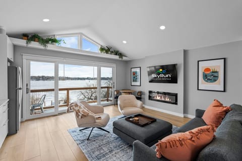 Stylish lounge area featuring a fireplace, smart TV, and peaceful lake backdrop