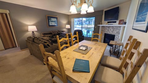 Living room with gas fireplace, dining table, and patio with propane BBQ grill