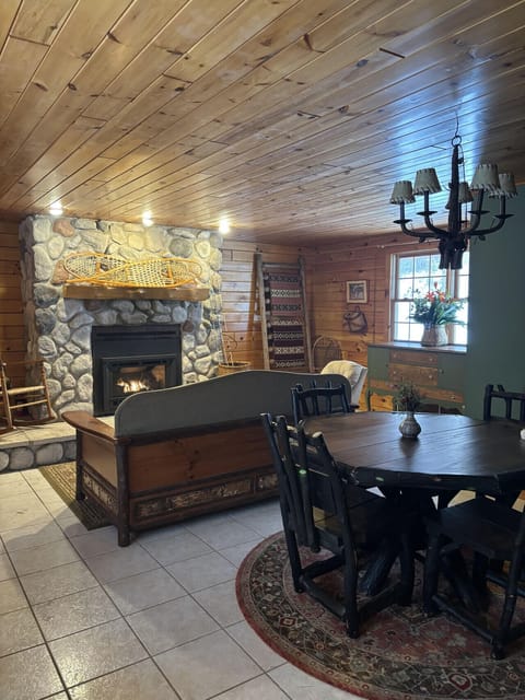 Bright Adirondack-style living room with warm wood accents, comfortable seating, fireplace, and large windows overlooking the 30-acre property. Newly renovated space designed for relaxing after exploring the private cabin’s trails and waterfall.