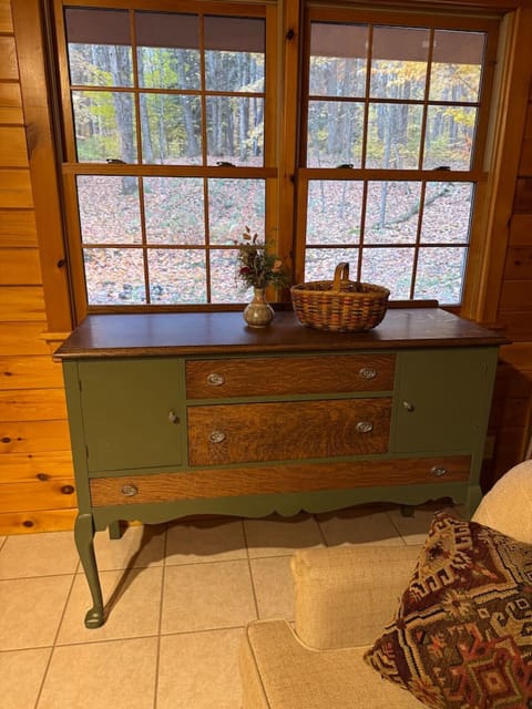 Adirondack-style living room with warm wood accents, comfortable seating, and large windows overlooking the 30-acre property. Newly renovated space