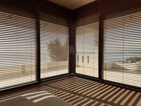 Master bedroom interior corner with wooden blinds filtering natural light