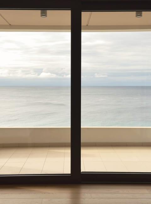 Master bedroom sea view framed by glazed sliding doors and terrace edge