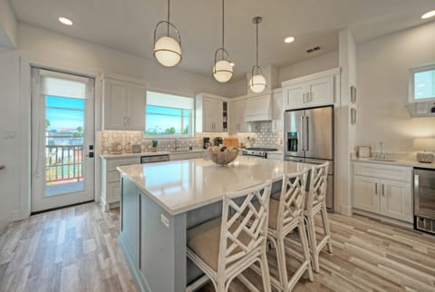 Open-concept kitchen with island, white cabinetry, and hanging pendant lights.
