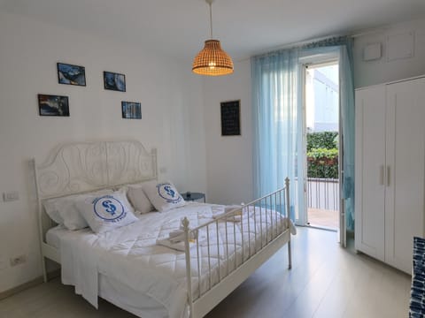 Bright double bedroom in an apartment located in the center of Sirmione, furnished in a modern style with a double bed, wardrobe, and direct access to the balcony. The room offers natural light and a view of the area outside the building, ideal for a comfortable stay in the heart of the town.