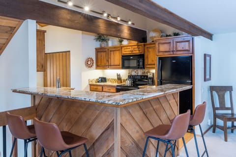 Gather around this stunning granite-topped island where rustic wood meets modern convenience in your mountain getaway kitchen.