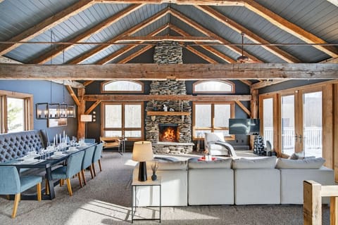The living room with original 1840s farmhouse beams, a cozy stone fireplace, and modern furniture for your comfort..