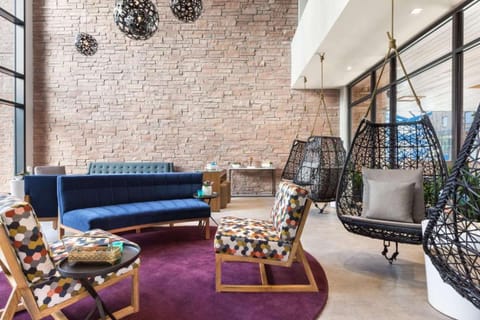 Lounge area with brick wall, blue sofa, and patterned chairs.
