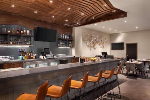 Bar area with orange stools, TVs, and wood ceiling accents.