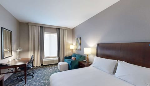 Bright bedroom with desk, chair, and seating by the window
