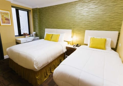 Two beds with yellow accents beside patterned green wall.