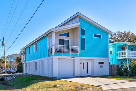 A vibrant turquoise coastal home with modern design and spacious garage, perfectly positioned in a quiet residential neighborhood.