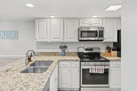 Modern kitchen featuring white cabinetry, granite countertops, and stainless steel appliances.