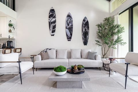 Sink into plush seating in your stylish living room, where surfboard art and natural light create the perfect coastal retreat atmosphere.