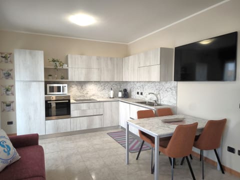 Fully equipped kitchen in the apartment in Peschiera del Garda, modern and functional, equipped with oven, microwave, and coffee machine. The bright room includes a comfortable dining area and a large TV, ideal for relaxing with family or friends.