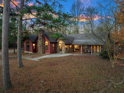 Rustic log cabin surrounded by towering trees offers a peaceful woodland retreat with warm lighting and natural charm.